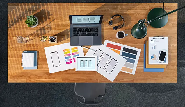 Бюро с лаптоп и дизайн идеи за мобилни устройства - Професионална уеб разработка за бизнес нужди и дигитални проекти - УебКома ООД