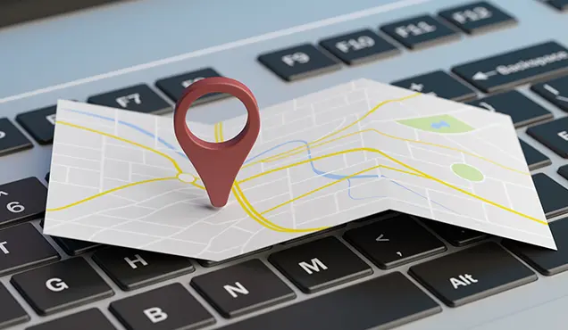 Клавиатура на лаптоп над която има карта и пин за местоположение - Професионална уеб разработка за бизнес нужди и дигитални проекти - УебКома ООД